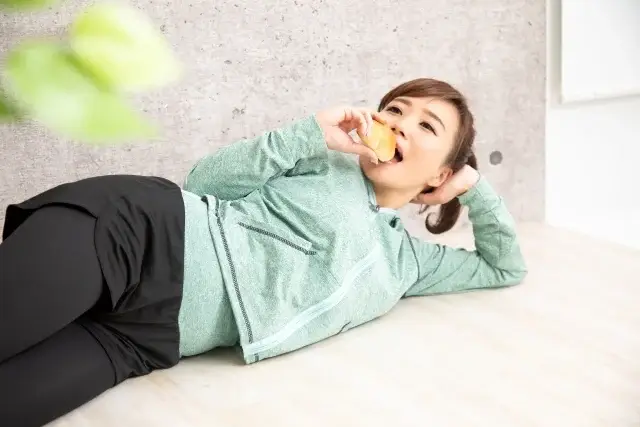 横になってパンを食べる女性
